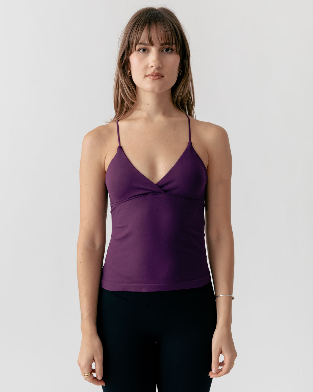 Woman wearing a purple camisole tank top against a white background