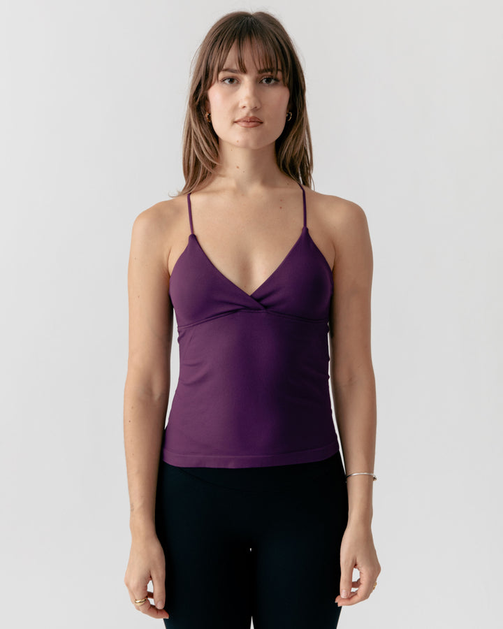 Woman wearing a purple camisole tank top against a white background