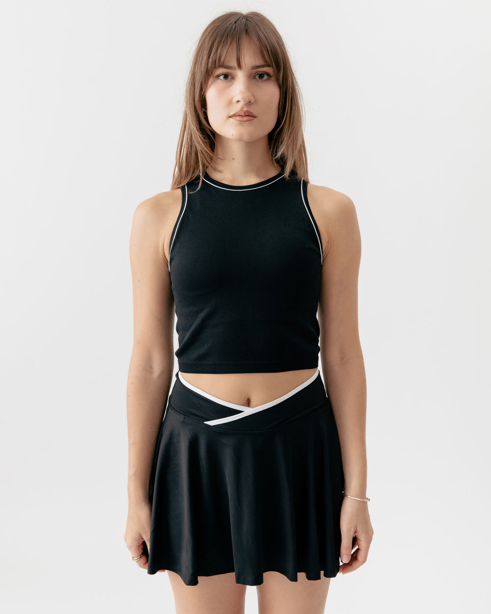 high-neck black crop tank top paired with a matching crossover V-waist tennis skirt
