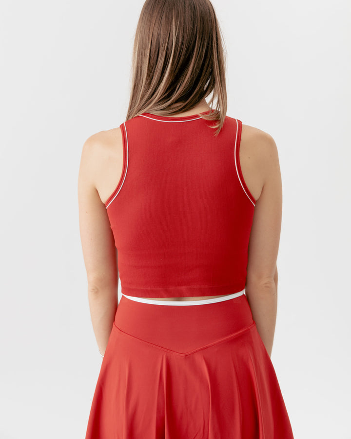 Red sleeveless top with white trim worn by a person on a light gray background
