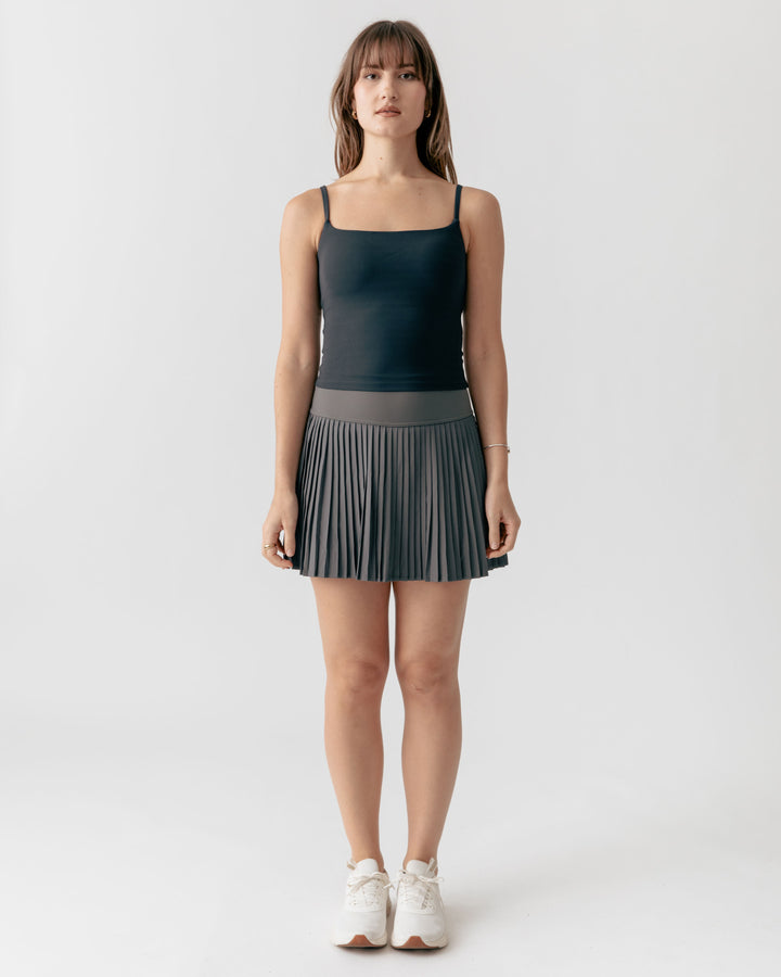 Woman wearing a black square neck camisole tank top and pleated skirt