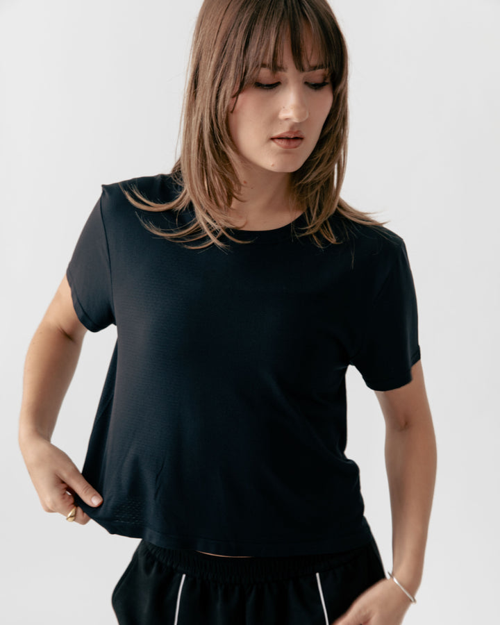 Woman wearing a black Cropped Crewneck t-shirt against a plain background