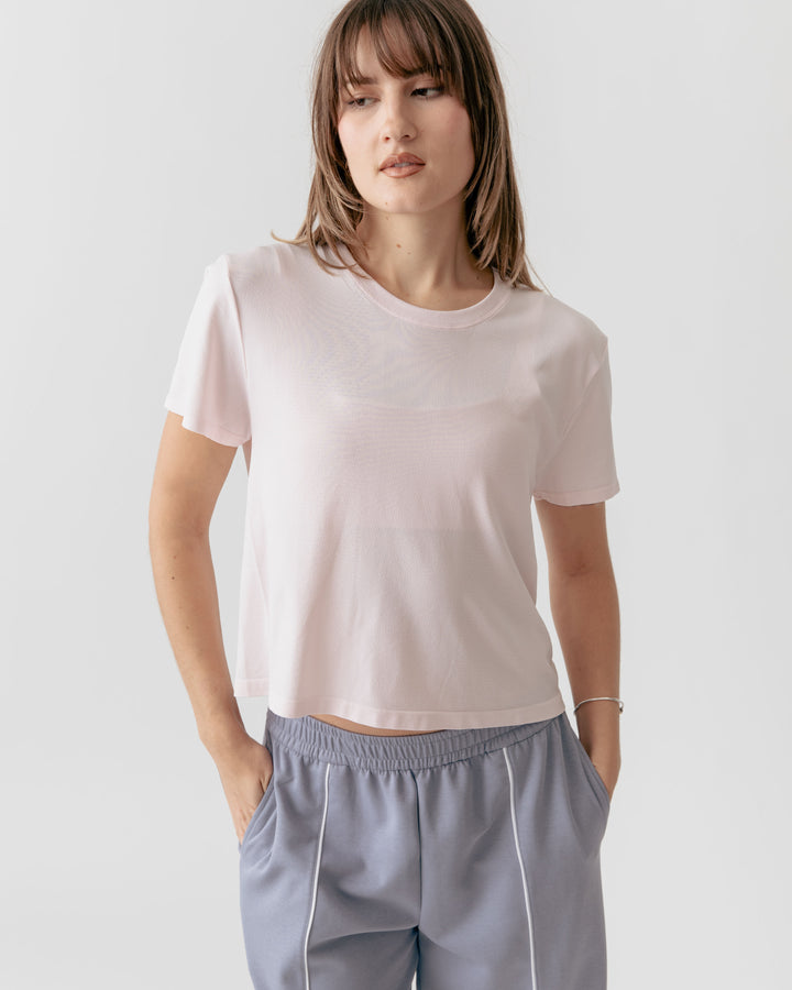 Woman wearing a Cropped Crewneck rose t-shirt and gray pants