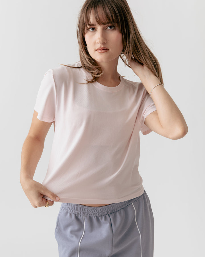Woman tugging the end of a lRose Cropped Crewneck t-shirt and gray pants