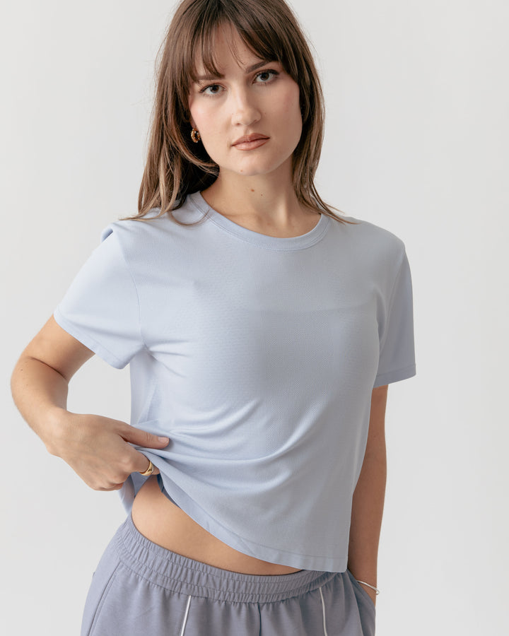 Woman tugged the end of a sky blue cropped crewneck t-shirt and pants