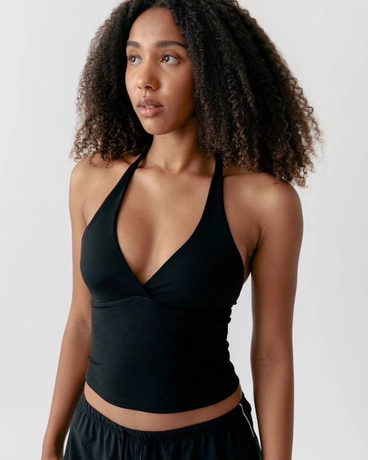 Woman wearing a black halter top against a plain background