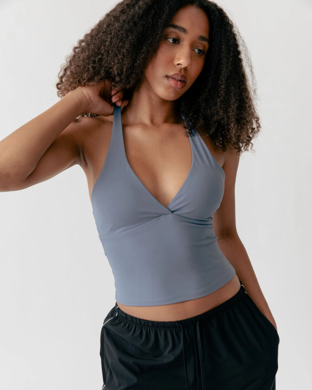 Woman wearing a light blue sports bra and black pants on a white background