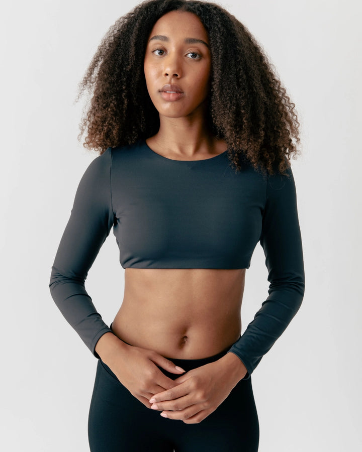 Woman wearing a dark long-sleeve athletic top against a plain background