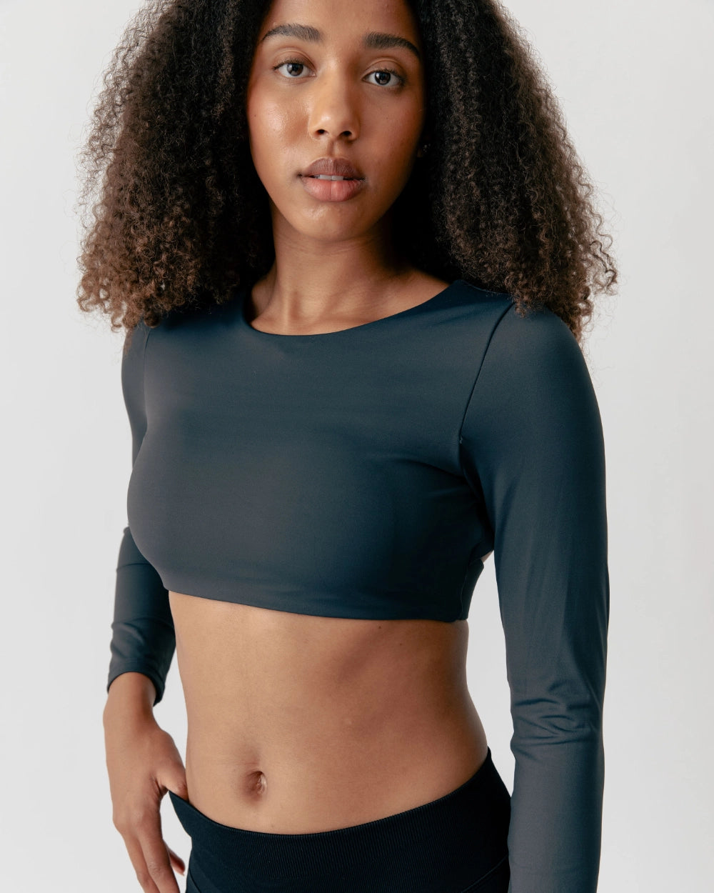Woman wearing a dark green long-sleeve athletic top against a plain background