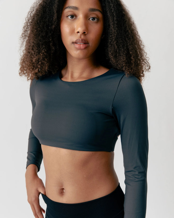 Woman wearing a dark green long-sleeve athletic top against a plain background