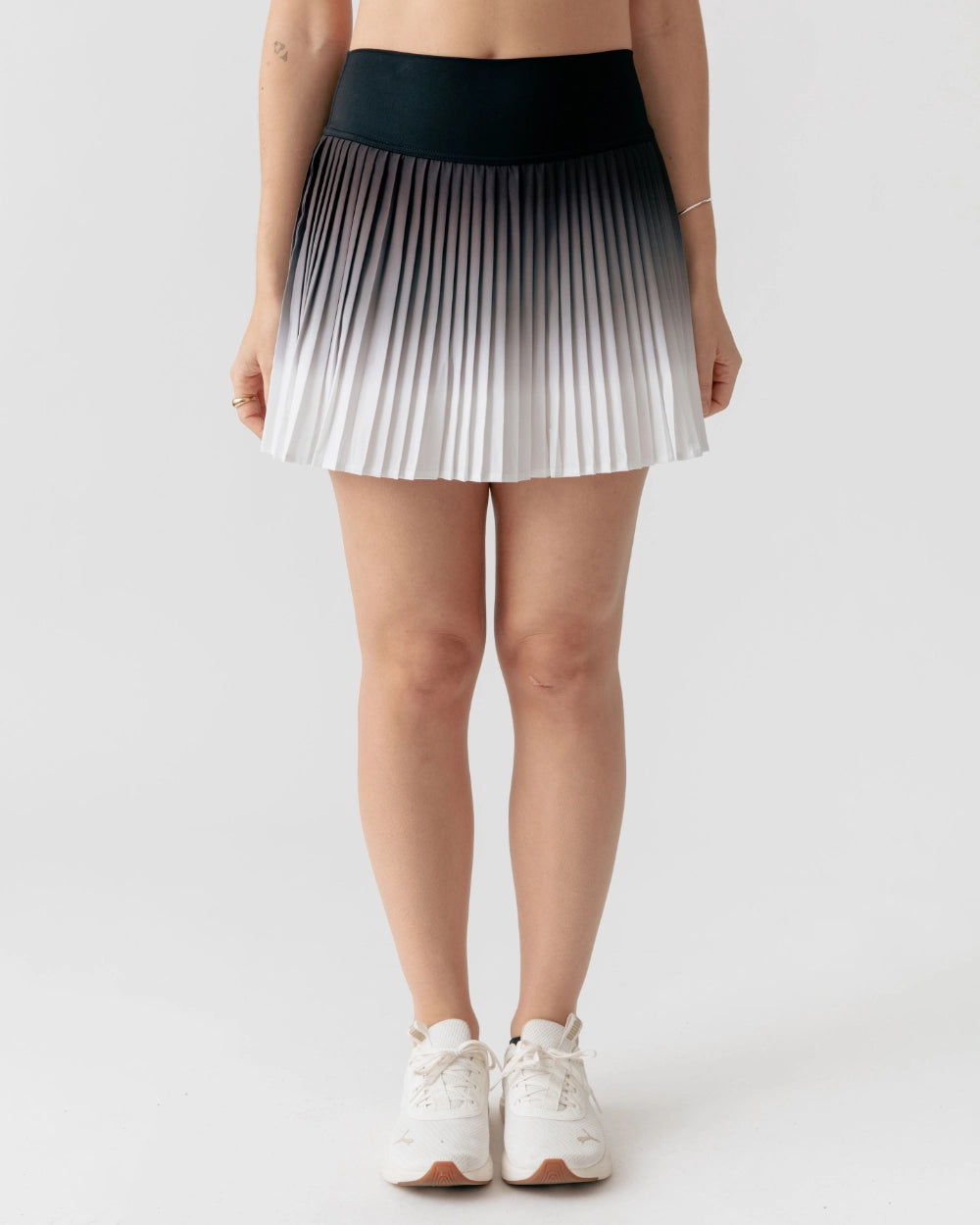 Person wearing a pleated skirt with a gradient design on a plain background
