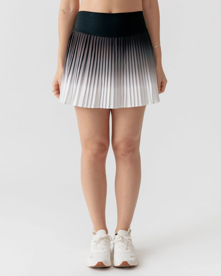Person wearing a pleated skirt with a gradient design on a plain background