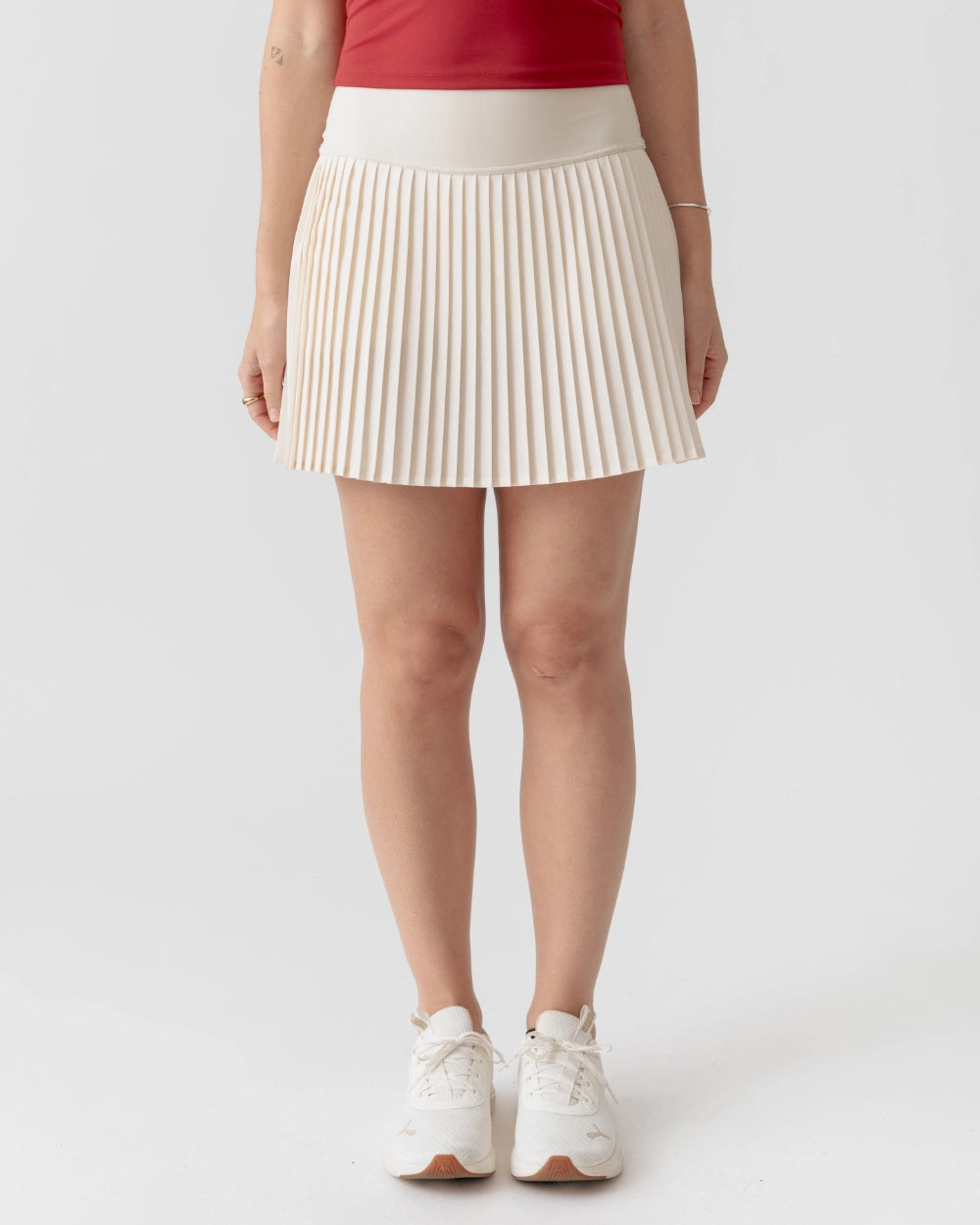Person wearing a white pleated skirt on a plain background