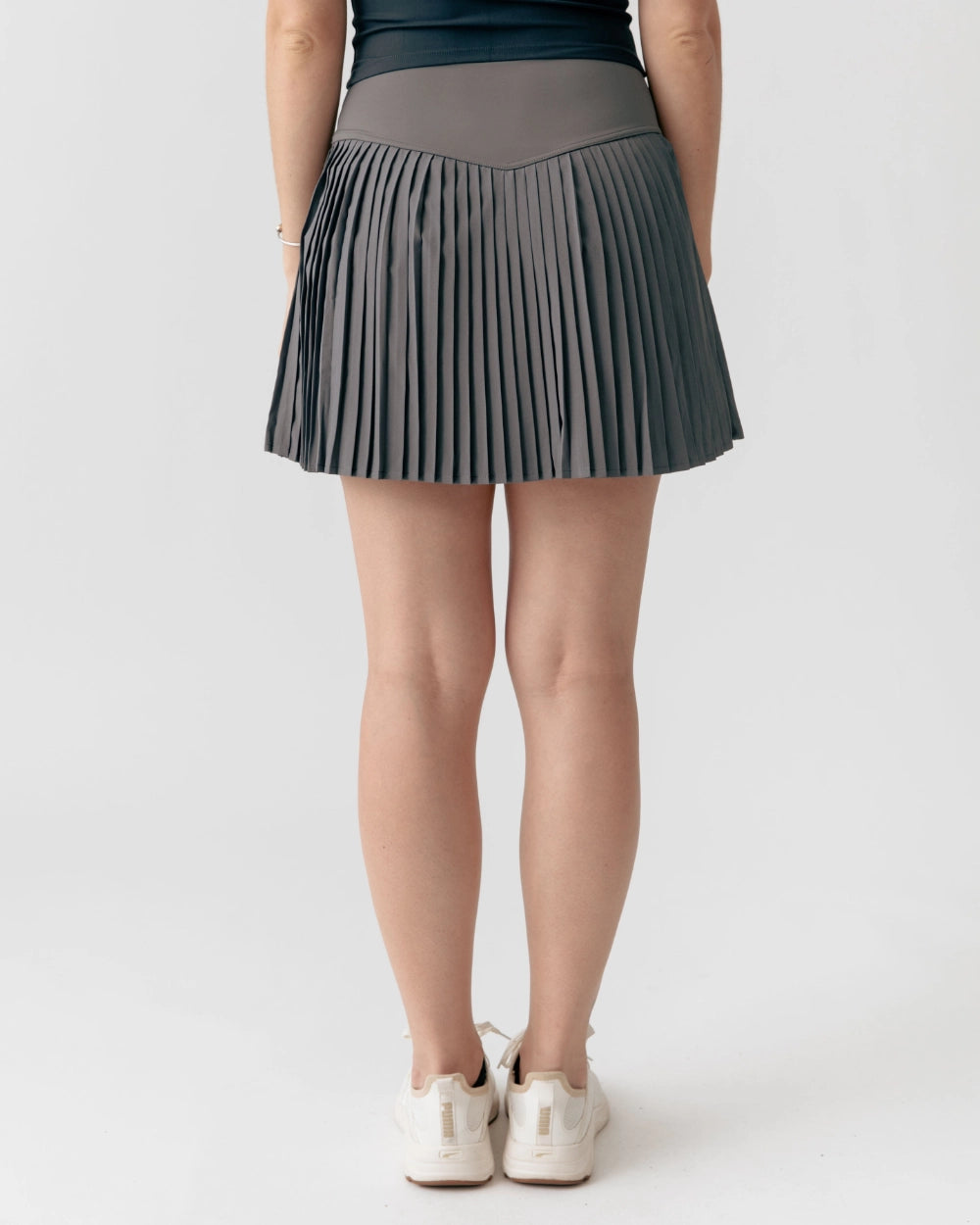 Person wearing a pleated gray skirt on a white background