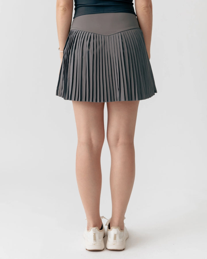 Person wearing a pleated gray skirt on a white background