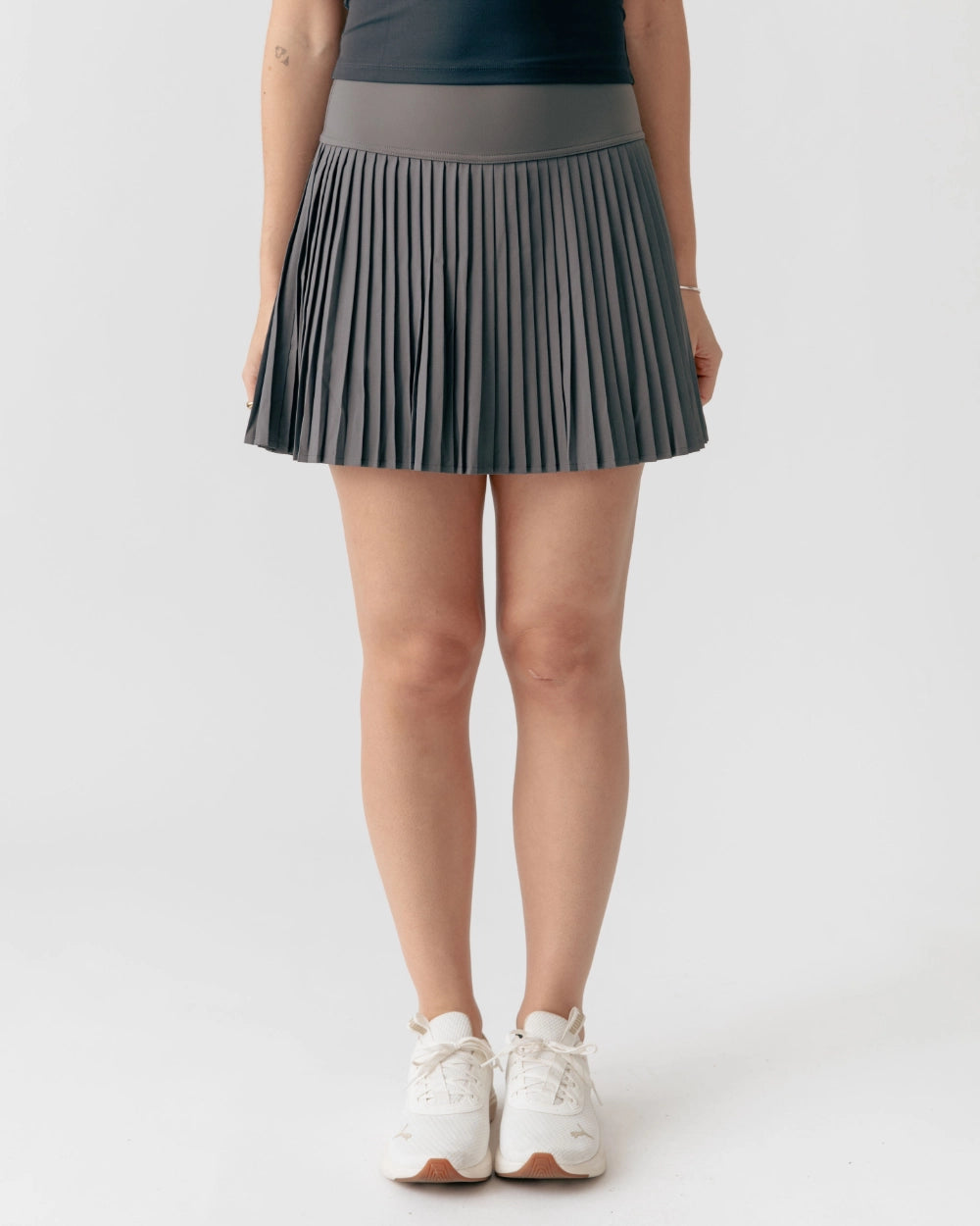 Person wearing a gray pleated skirt on a white background