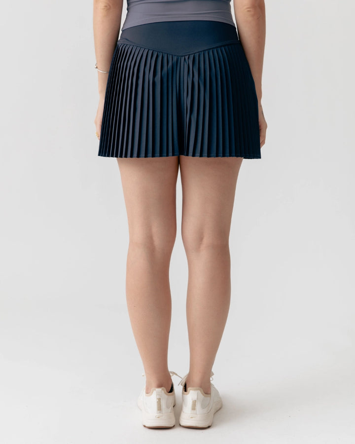 Person wearing a pleated navy skirt on a white background