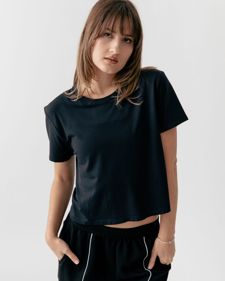 Female wearing a black cropped crewneck and black pants with white trim