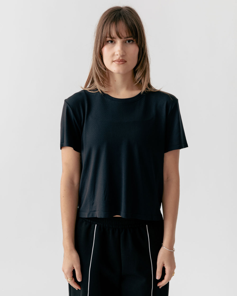 Person wearing a Cropped Crewneck black t-shirt and black pants with white stripes
