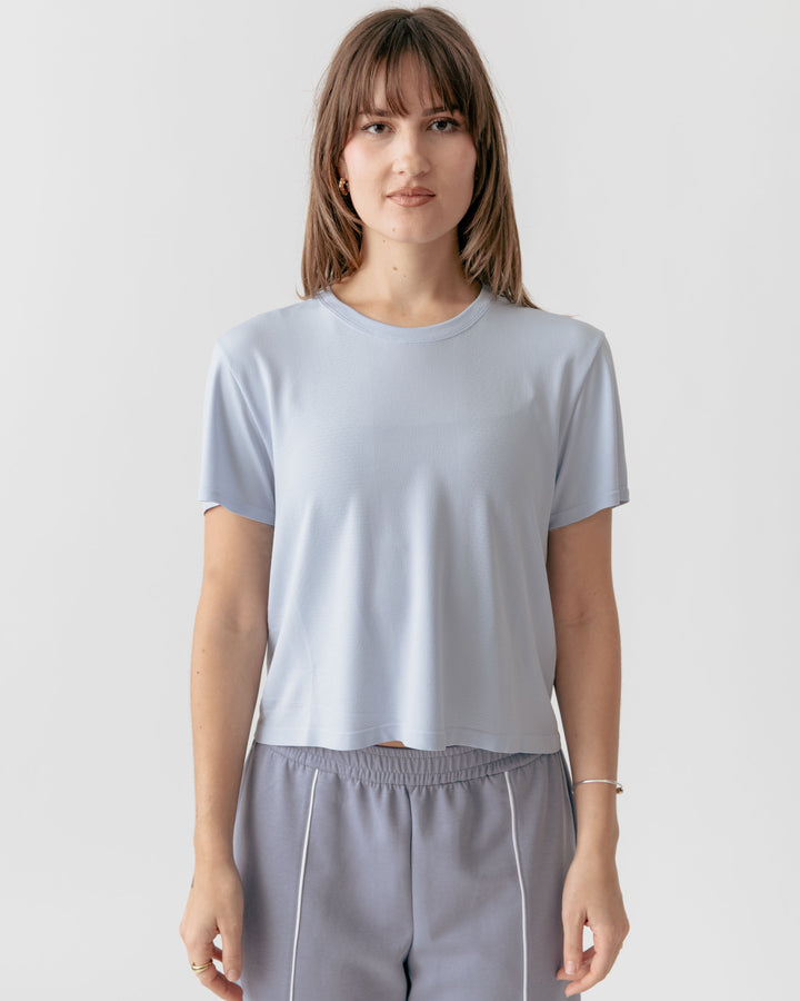 Person wearing a sky blue cropped crewneck t-shirt and gray pants