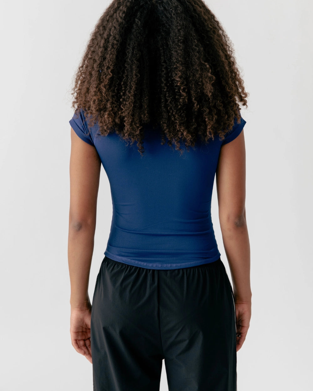 Person wearing a blue top and black pants on a white background
