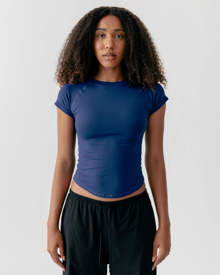 Woman wearing a blue athletic top and black pants on a white background
