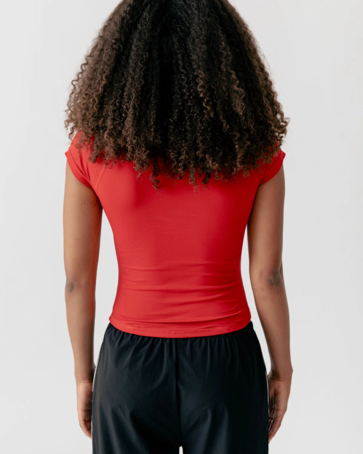 Person wearing a red top and black pants on a white background