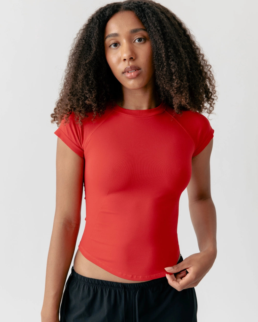Person wearing a red crop top against a plain background