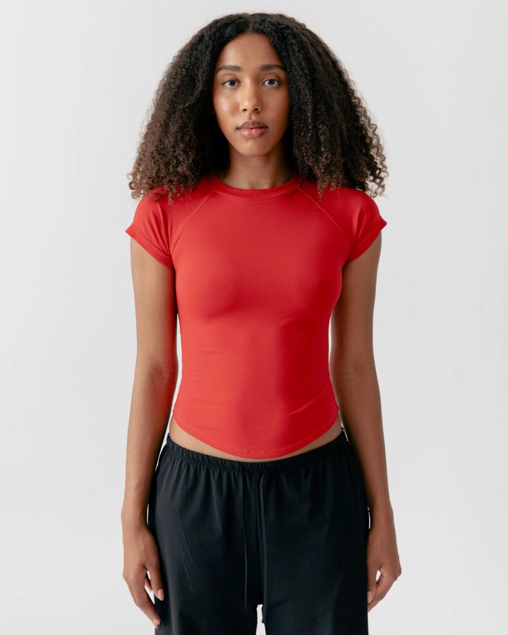 Woman wearing a red athletic top and black pants on a white background
