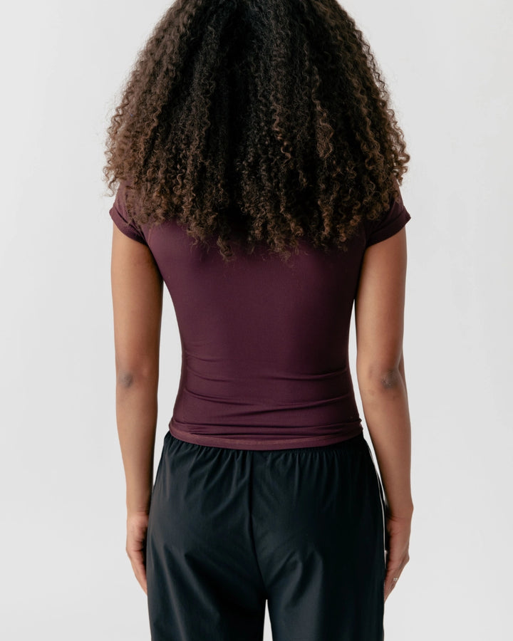 Person wearing a maroon top and black pants on a plain background