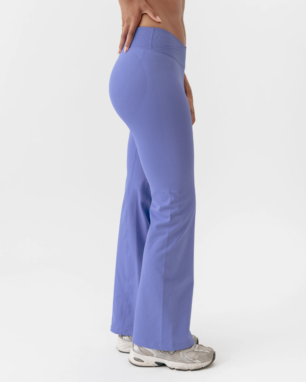 Person wearing purple flared pants on a white background