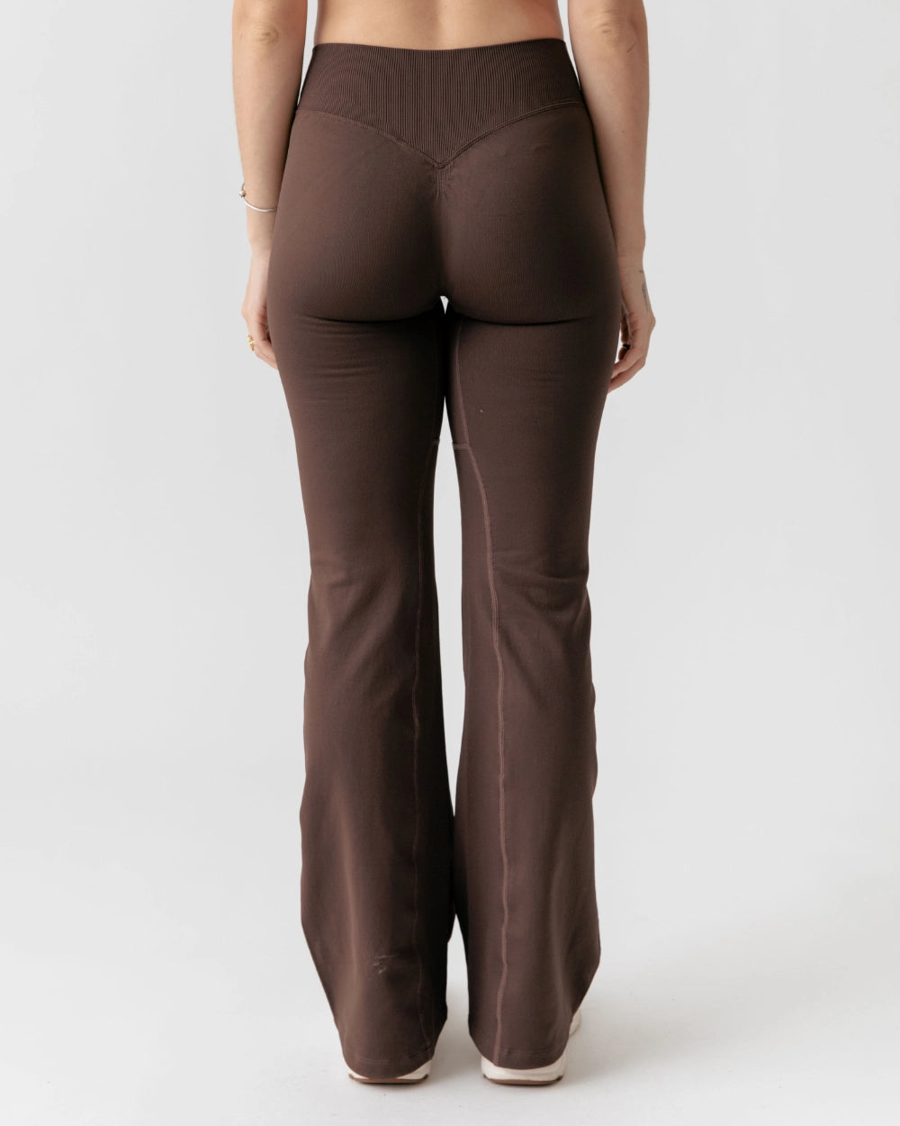 Brown flared pants worn by a person on a white background