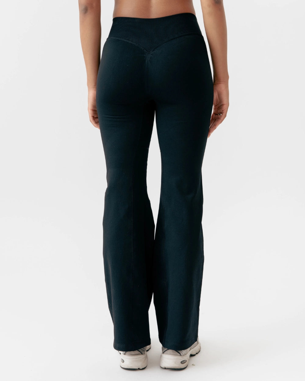 Person wearing dark green yoga pants on a white background