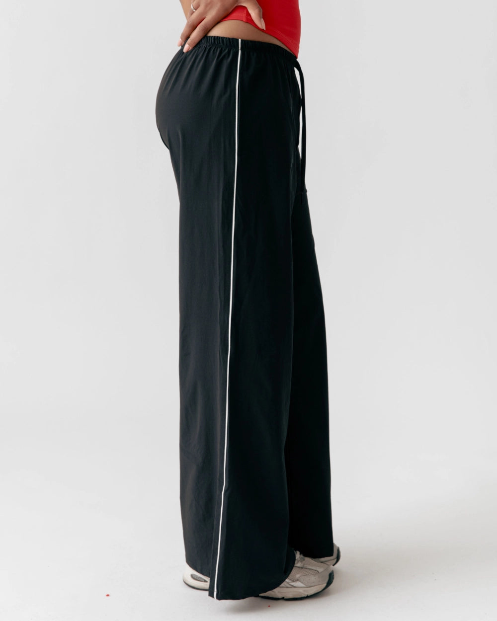Black wide-leg pants with a white stripe on a white background