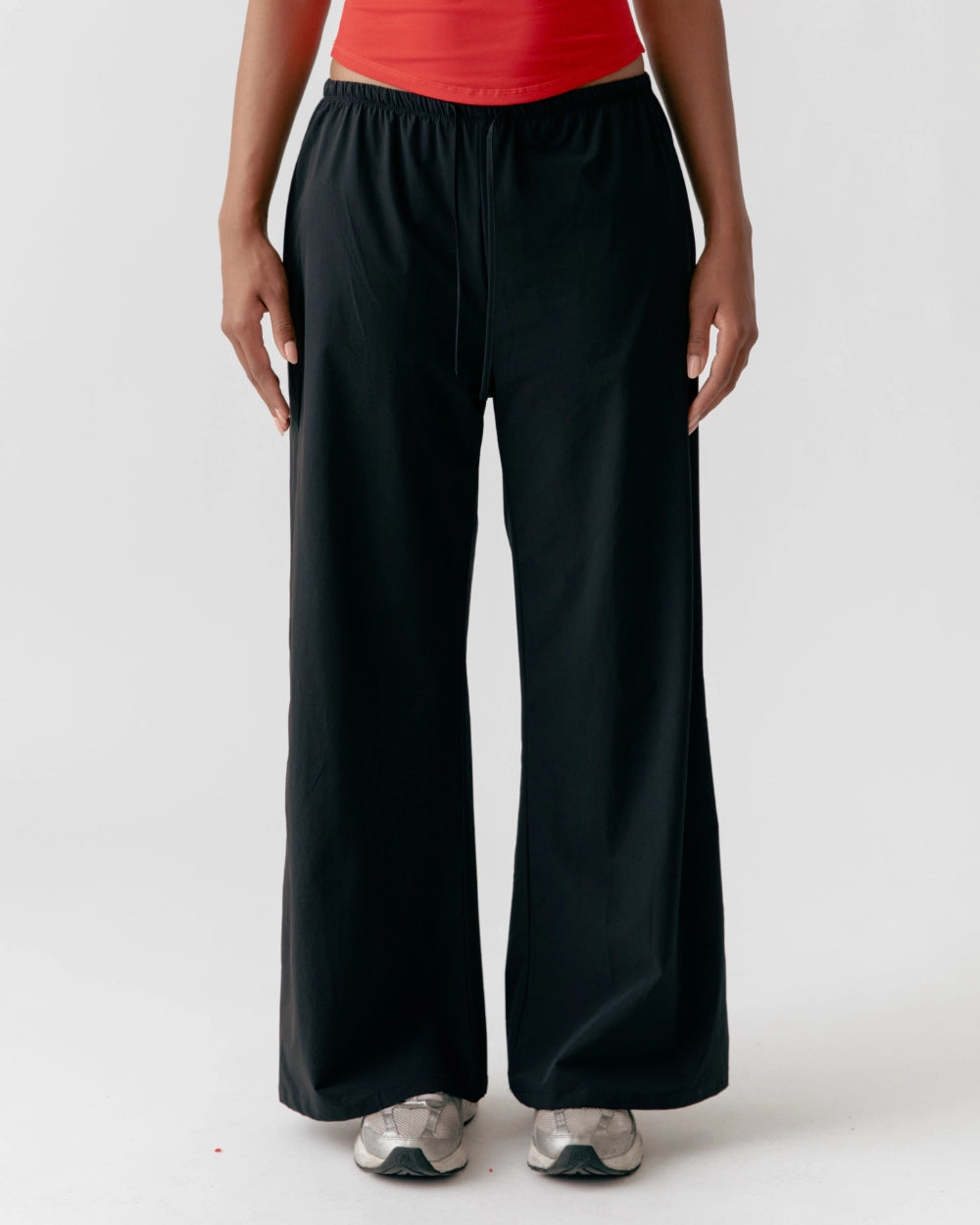 Person wearing black wide-leg pants and a red top on a white background