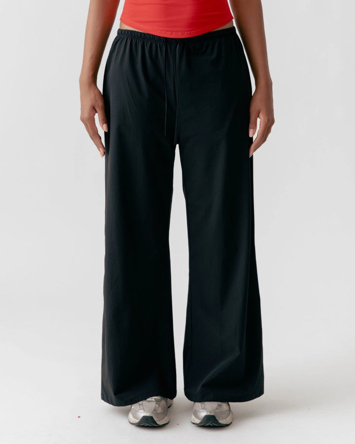 Person wearing black wide-leg pants and a red top on a white background