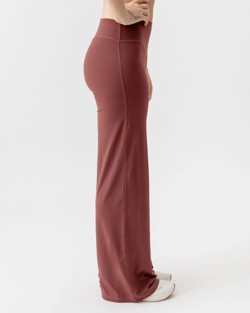 Person wearing brown high-waisted pants on a white background
