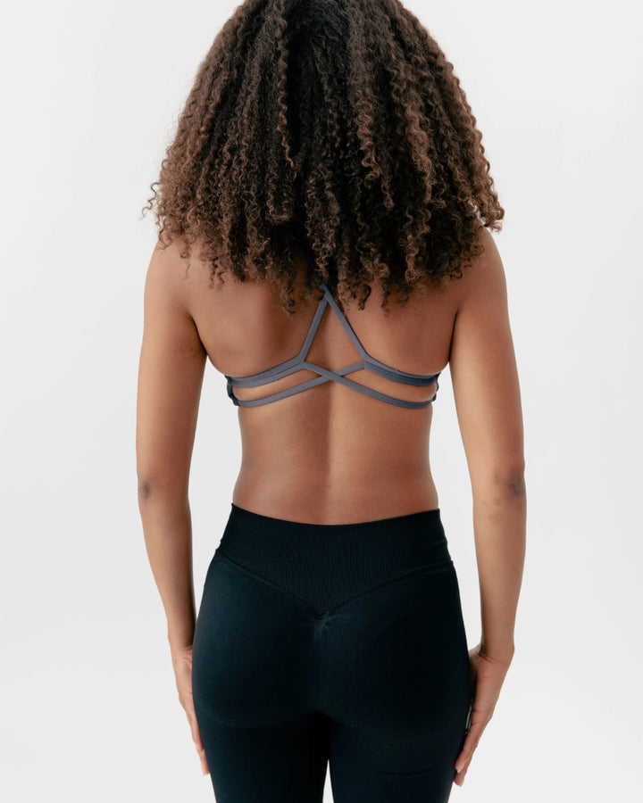 Person wearing a strappy top and black leggings on a white background