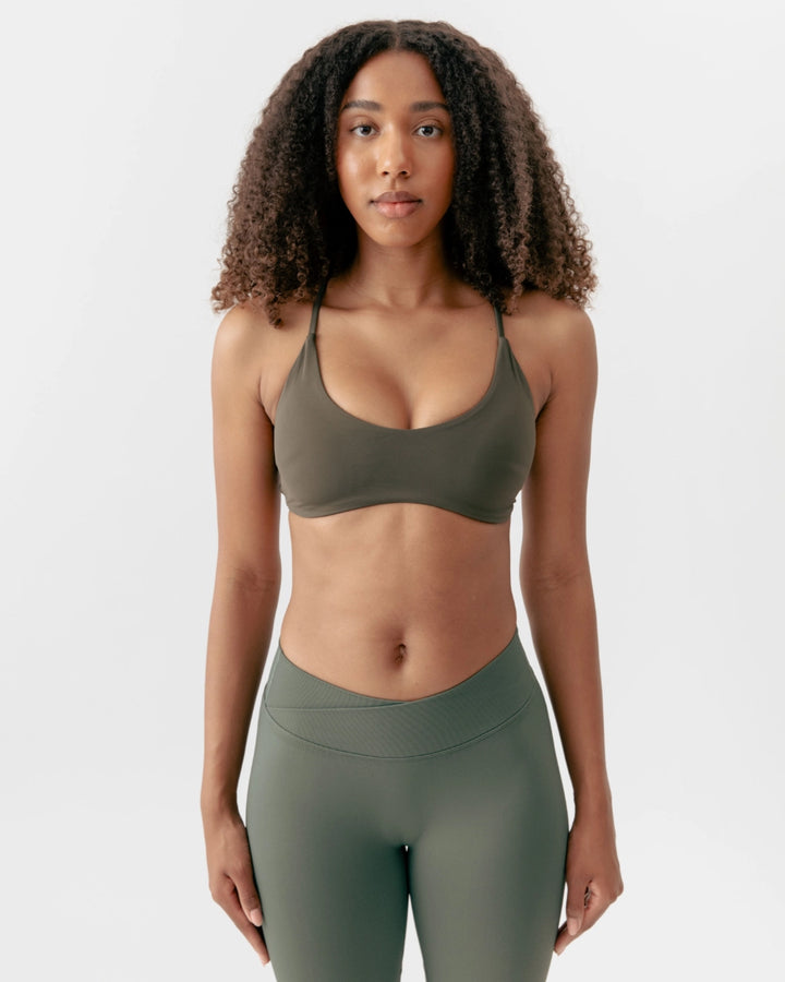 Woman wearing a green sports bra and leggings on a white background