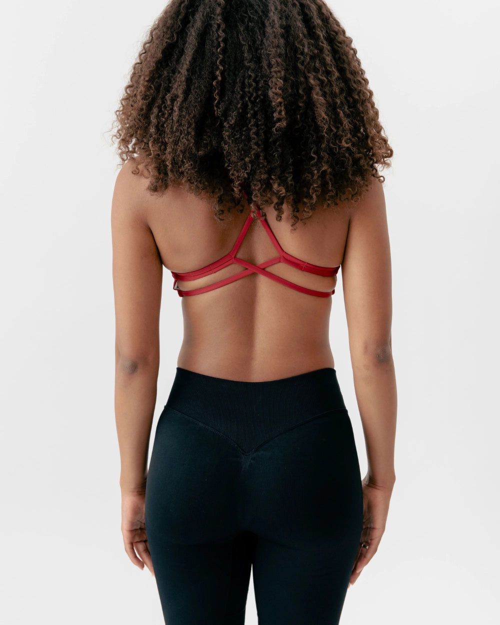 Person wearing a red strappy top and black leggings on a plain background