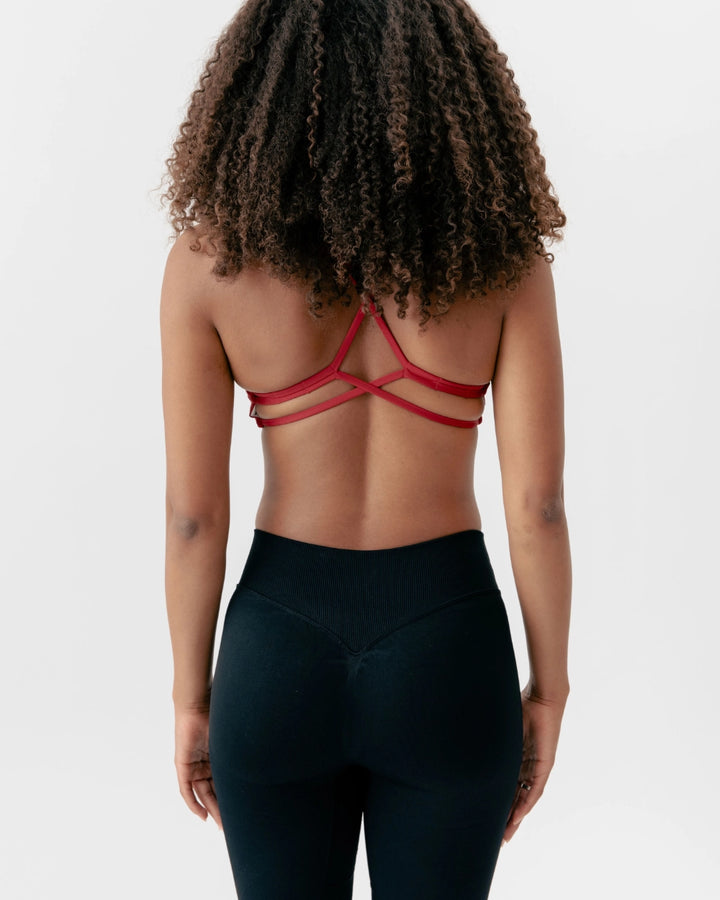 Person wearing a red strappy top and black leggings on a plain background