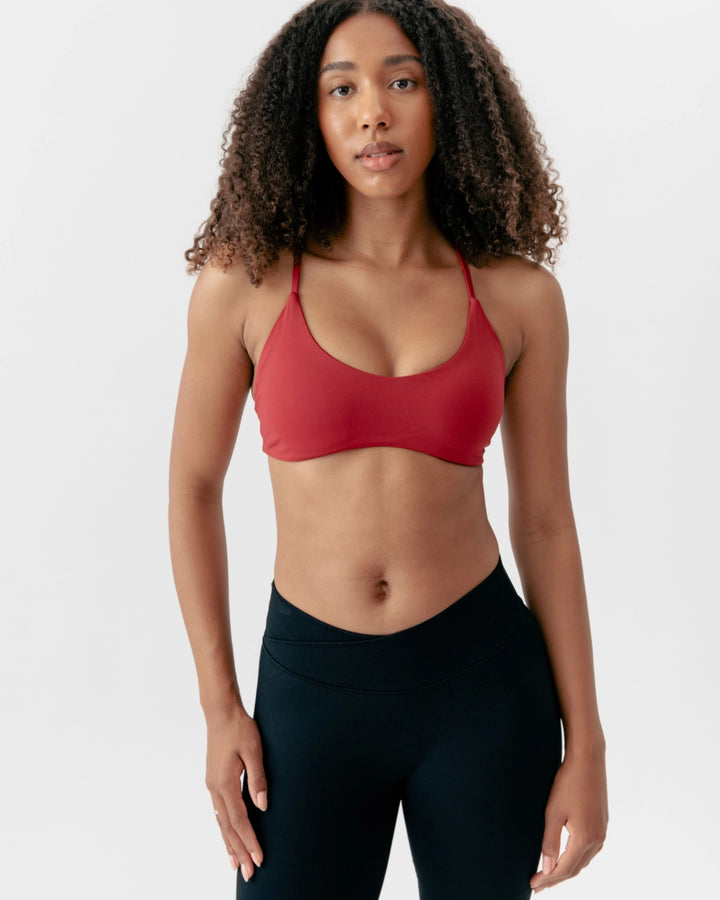 Woman wearing a red sports bra and black leggings on a white background