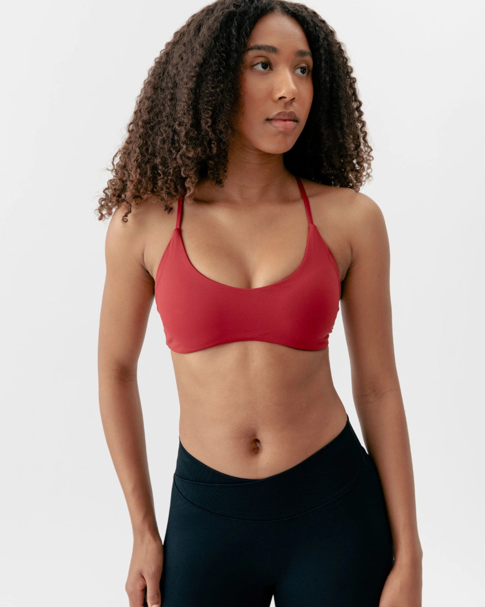 Woman wearing a red sports bra and black leggings on a white background